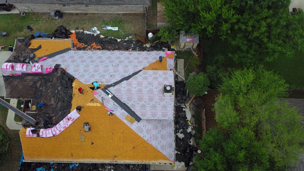 Aerial view of a residential roof replacement showing exposed roof decking and underlayment installation.